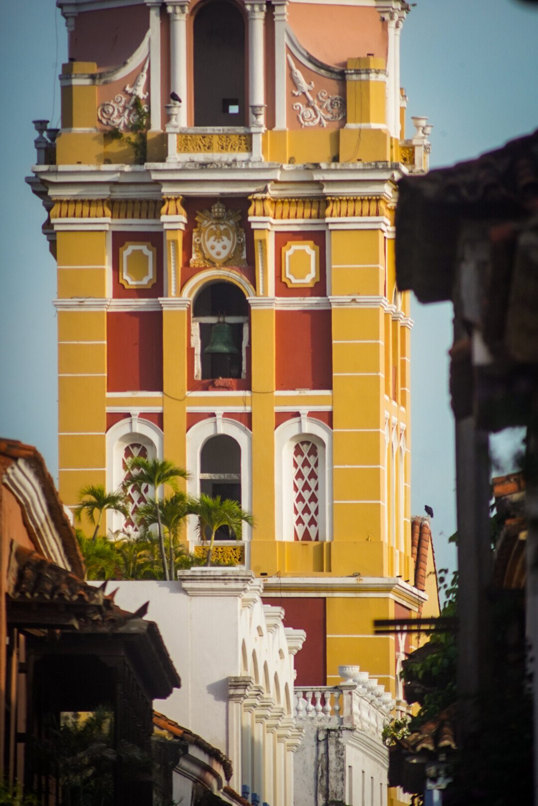 Vista de una calle angosta de Cartagena con balcones y una cúpula al fondo