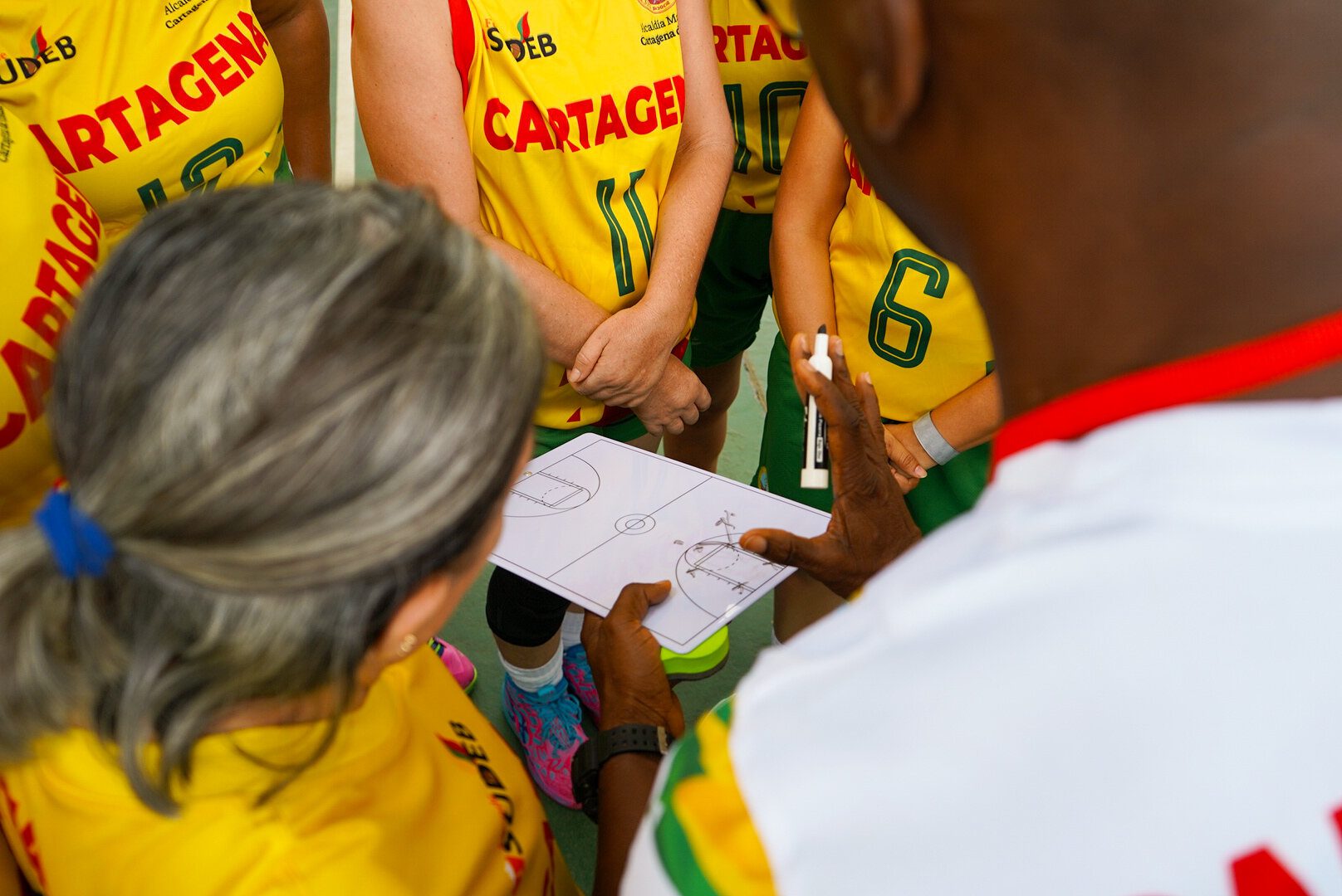 Entrenadora explicando una jugada de baloncesto en una pizarra táctica