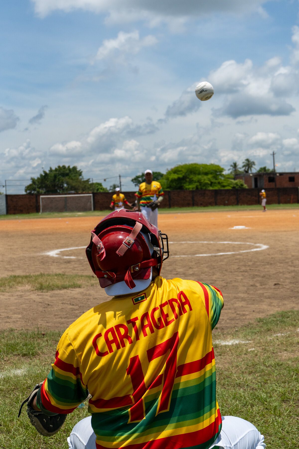 Receptor de béisbol con casco observando una bola en el aire
