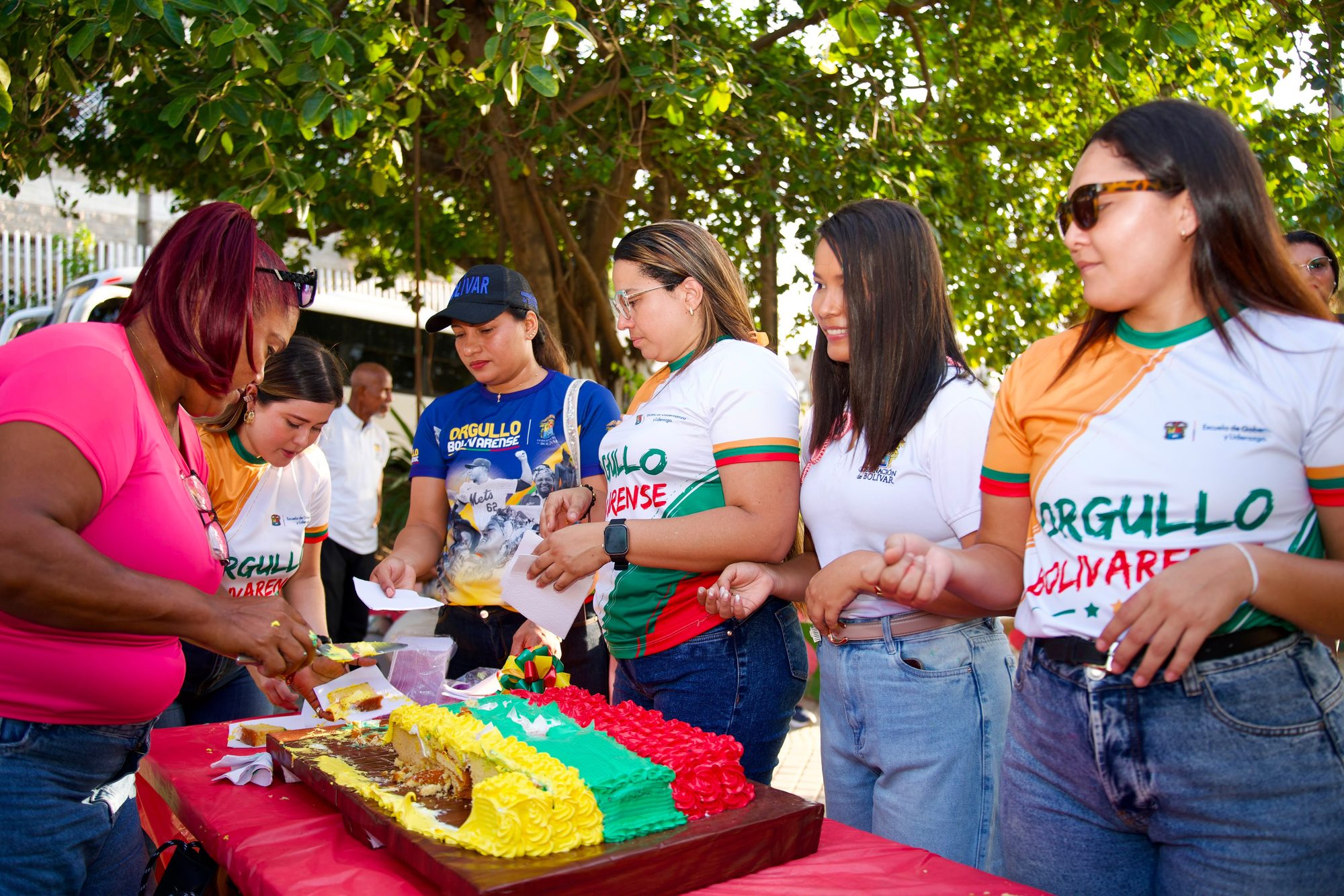 Grupo de mujeres cortando un pastel tricolor con camisetas de Orgullo Bolivarense