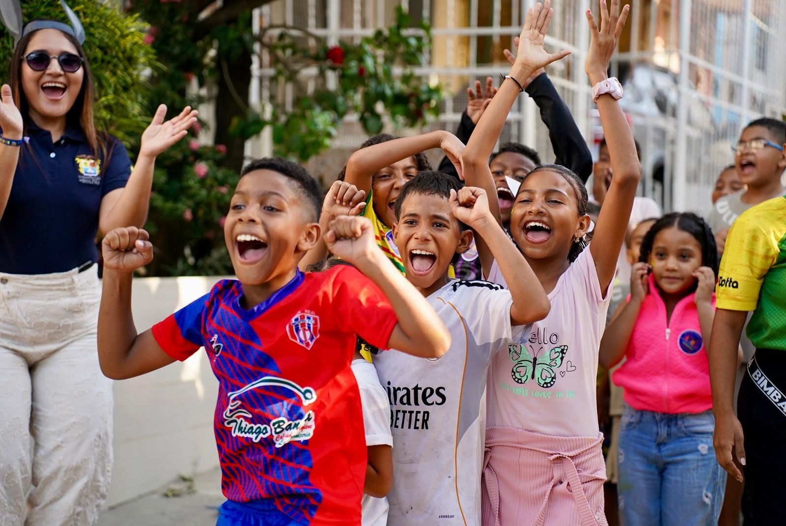 Grupo de niños celebrando con las manos en alto en la calle