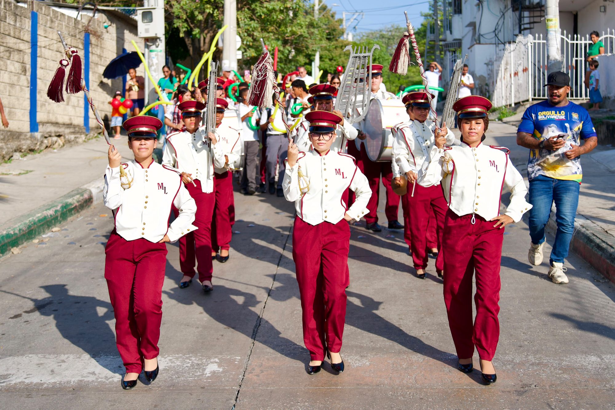 Banda marcial desfilando por una calle con tambores y liras