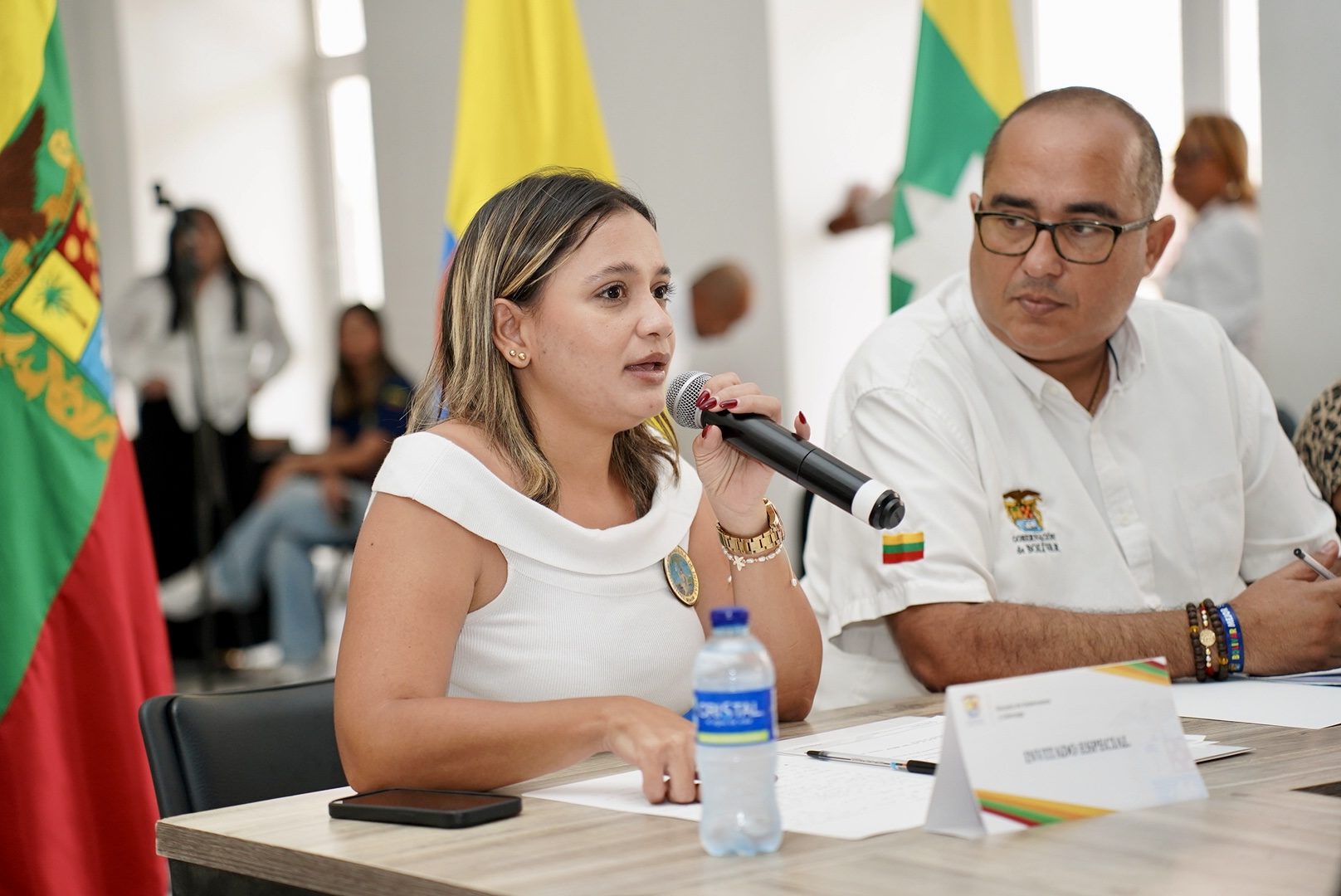 Mujer interviniendo con micrófono en una mesa de panel institucional