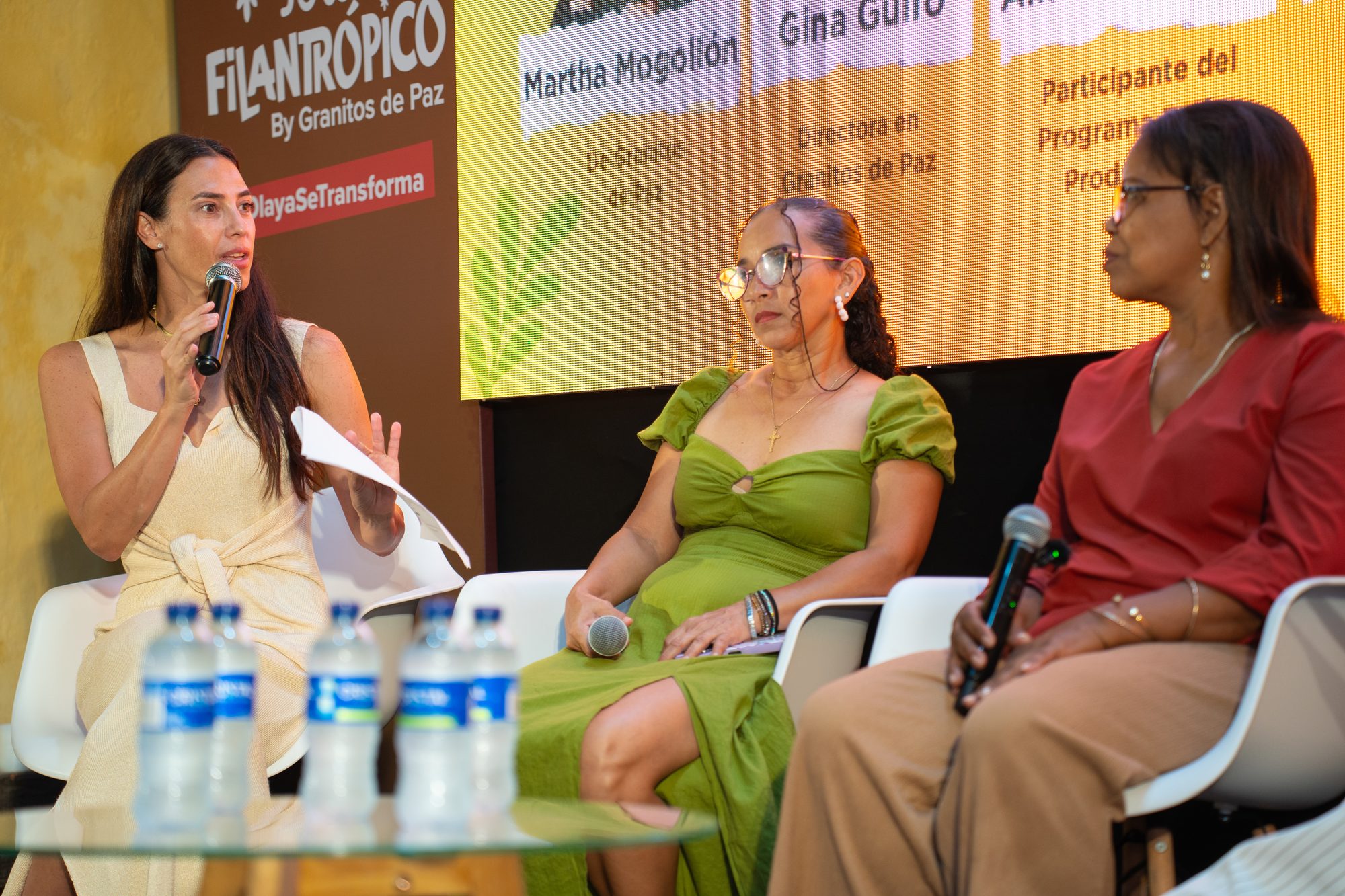 Panel de conversación con tres mujeres frente al backdrop de Tour Filantrópico By Granitos de Paz