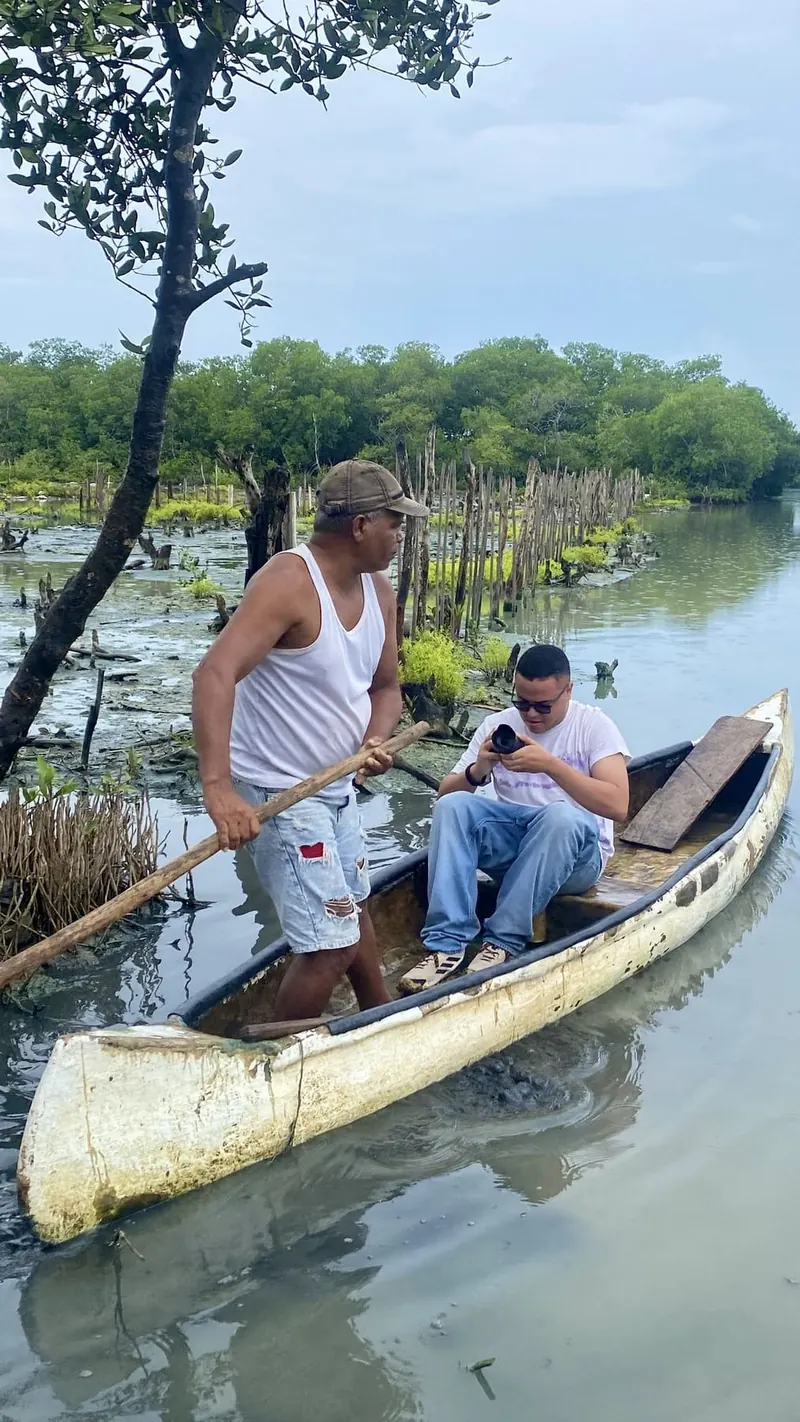 Camilo revisando la cámara a bordo de una canoa en la ciénaga junto a un pescador