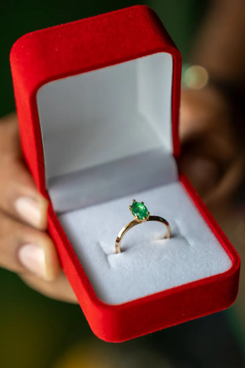 Mujer sosteniendo un estuche rojo con un anillo de esmeralda